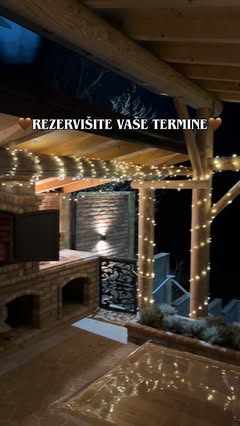 Natkrivena terasa sa roštiljem od cigle i svetlima uveče